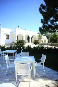 un groupe de tables et de chaises avec un bâtiment en arrière-plan dans l'établissement Villa Curri, à Locorotondo