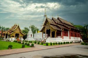 a group of temples in a park with a cloudy sky at Canary House Rachawong คานารี่ เฮ้าส์ ราชวงศ์ in Chiang Mai