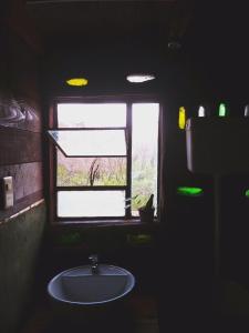 uma casa de banho escura com um lavatório e uma janela em Raices del Mar em La Pedrera