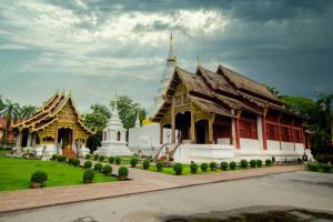 Un groupe de temples dans un parc avec un ciel nuageux dans l'établissement Born Guest House, à Chiang Mai