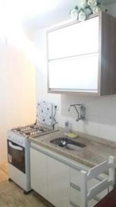 a kitchen with a sink and a stove at Village dos Pássaros Apartamento in Guarapari