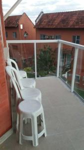 two white chairs and a stool on a balcony at Village dos Pássaros Apartamento in Guarapari