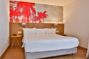 a bedroom with a large bed with a red painting on the wall at Radisson RED Campinas in Campinas +170 photos