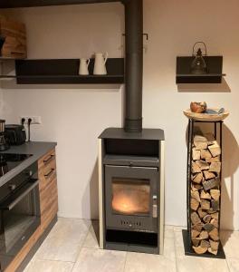 a kitchen with a stove with a pile of logs at Zirben Appartement zwischen Berg und See in Steindorf am Ossiacher See