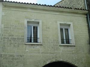 dos ventanas en el lateral de un edificio de ladrillo en Appartement sur Sommières jusqu'à 6 personnes en Sommières