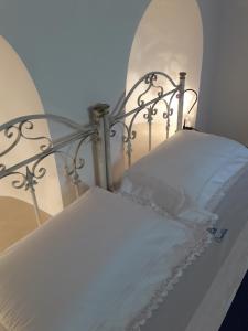 Cama blanca con sábanas y almohadas blancas en Trulli Convertini, en Locorotondo