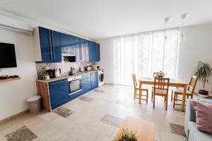 uma cozinha e sala de jantar com armários azuis e uma mesa em Rákóczi Prime em Sopron