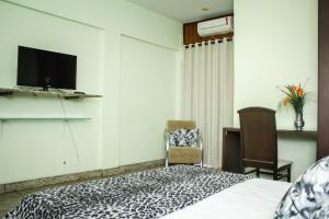 Riviera Palace Hotel في سيت لاغواس: غرفة نوم مع سرير وتلفزيون على الحائط