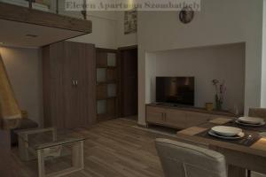 a living room with a television and a table and chairs at Eleven Apartman in Szombathely