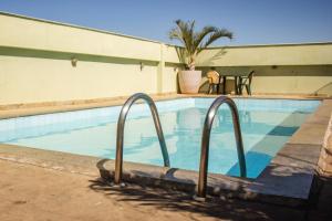 uma piscina com dois carris de metal ao lado de um edifício em Riviera Palace Hotel em Sete Lagoas