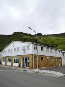 a white building with a black roof on the side of the road at Puffin Hotel Vík in Vík