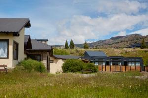 una casa en un campo con montañas en el fondo en Hosteria El Puma en El Chalten