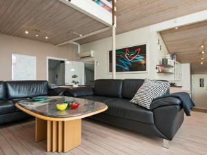 ein Wohnzimmer mit einem schwarzen Sofa und einem Tisch in der Unterkunft 10 person holiday home in Ebeltoft in Ebeltoft
