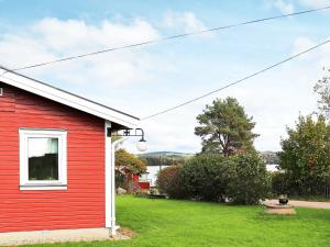 una casa rossa con un cortile verde con finestra di 4 person holiday home in VESSIGEBRO a Vessigebro
