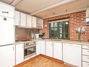 a kitchen with white cabinets and a brick wall at 6 person holiday home in Ulfborg in Øhuse