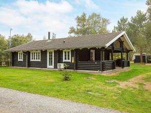a log cabin with a porch and grass at 6 person holiday home in R dby in Rødby
