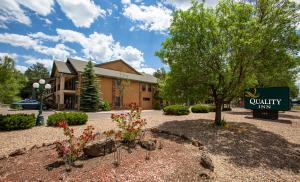 un panneau indiquant une auberge de campagne avec un bâtiment dans l'établissement Quality Inn Pinetop Lakeside, à Pinetop-Lakeside