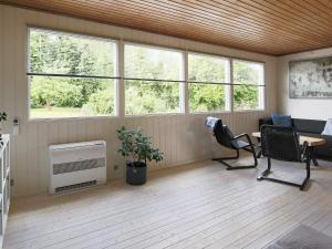 uma sala de estar com janelas e uma mesa e cadeiras em 5 person holiday home in J gerspris em Jægerspris