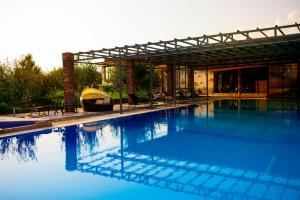 a large blue swimming pool with a pergola at Twins Wine House in Napareuli