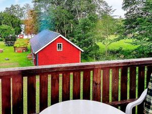 a red barn with a table on a wooden deck at 5 person holiday home in LAMMHULT SVERIGE in Förhult