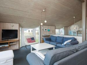 een woonkamer met een blauwe bank en een tv bij 10 person holiday home in Henne in Henne