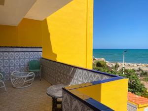 un bâtiment jaune avec une table et des chaises et l'océan dans l'établissement 1era linea de playa VILLA MARGARET Cullera Marenyet, à Cullera