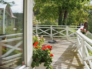 uma varanda com uma cerca branca e flores sobre ela em 4 person holiday home in VALDEMARSVIK em Valdemarsvik