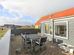 een patio met een tafel en stoelen en een huis bij 6 person holiday home in Lemvig in Ferring