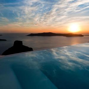 a pool with a view of the ocean and the sunset at Kapari Natural Resort in Imerovigli