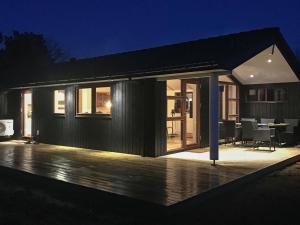 a black house with a deck at night at 6 person holiday home in R m in Lakolk