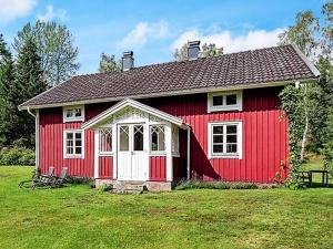 ein rotes Haus mit weißem Dach auf einem Feld in der Unterkunft Holiday home SKILLINGARYD in Skillingaryd