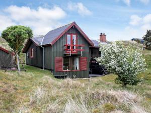 a green house with red doors and windows at 4 person holiday home in Fan in Fanø