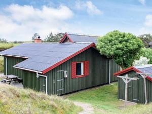 a green shed with a red door and a red window at 4 person holiday home in Fan in Fanø