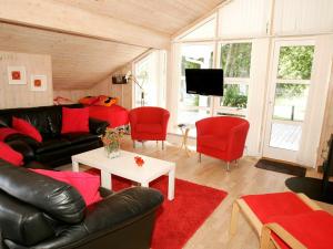 Vester Sømarkenにある8 person holiday home in Aakirkebyのリビングルーム(黒い革張りのソファ、赤い椅子付)