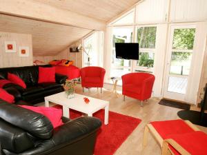 a living room with a black leather couch and red chairs at 8 person holiday home in Aakirkeby in Vester Sømarken