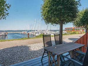 a wooden table and chairs next to a tree and a marina at 6 person holiday home in Ebeltoft in Ebeltoft