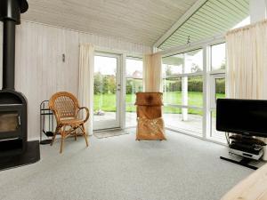 a living room with a fireplace and a chair and a television at Three-Bedroom Holiday home in Hejls 7 in Hejls