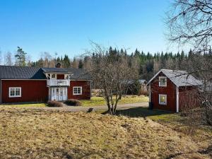 a red house and a barn in a field at 6 person holiday home in STOCKARYD in Stockaryd