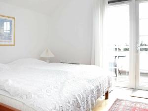 a white bedroom with a white bed and a window at 4 person holiday home in Blåvand-By Traum in Blåvand