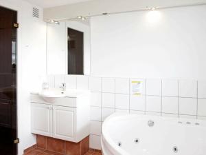 a white bathroom with a tub and a sink at 4 person holiday home in Blåvand-By Traum in Blåvand +34 photos