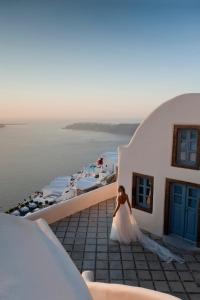 a bride standing on the balcony of a building at Kapari Natural Resort in Imerovigli