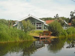 une maison assise sur le côté d'une masse d'eau dans l'établissement 6 person holiday home in Otterndorf, à Otterndorf