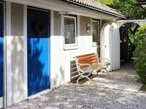 un banco de madera sentado fuera de una casa con una puerta azul en 3 person holiday home in H LLVIKEN en Höllviken