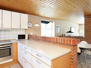 una cocina con armarios blancos y una pared de ladrillo en 8 person holiday home in Bl vand en Blåvand