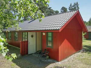 a red shed with a chair in a yard at 6 person holiday home in Nex in Snogebæk