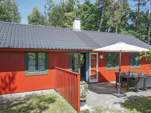 a small red house with a table and an umbrella at 6 person holiday home in Nex in Snogebæk