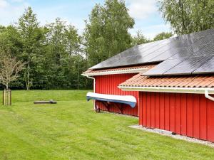 a red barn with a black roof in a field at 6 person holiday home in Otterndorf in Otterndorf