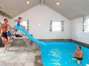 a group of men in a swimming pool with a slide in a swimming pool at 20 person holiday home in L kken in Nørre Lyngby