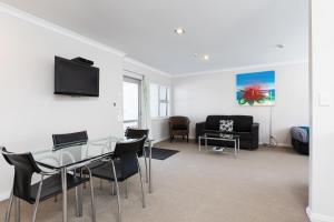 a living room with a glass table and chairs at Beach Street Motel Apartments in New Plymouth