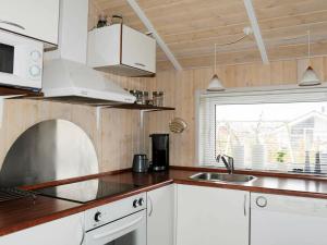 ÅrøsundにあるHoliday Home Raade IIIの白いキャビネット、シンク、窓付きのキッチン
